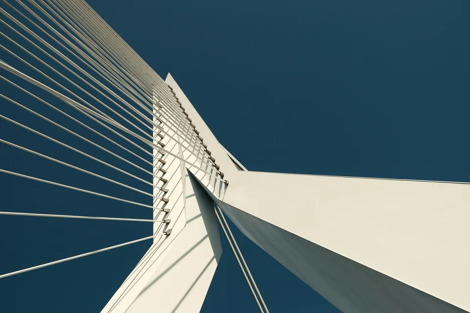 Looking up a white bridge pylon against a deep blue sky, with dozens of cables converging on the one structure.